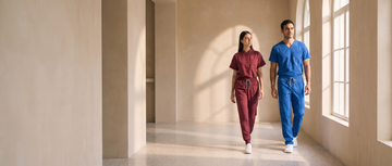 Two clinicians in Paeon scrubs walking a sunlit hospital corridor