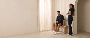 A woman in the Paeon Off-Duty Set and a man in the Chill Cut Oversized Shirt in a sunlit apartment